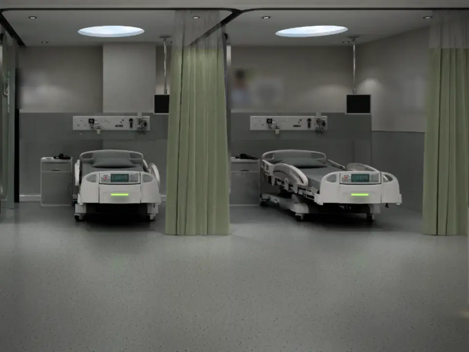 Render detail of a recovery bay: a hospital bed and its control panel beneath a wall-mounted monitor and a bedhead panel of medical gas outlets and sockets, beside a drawn curtain.